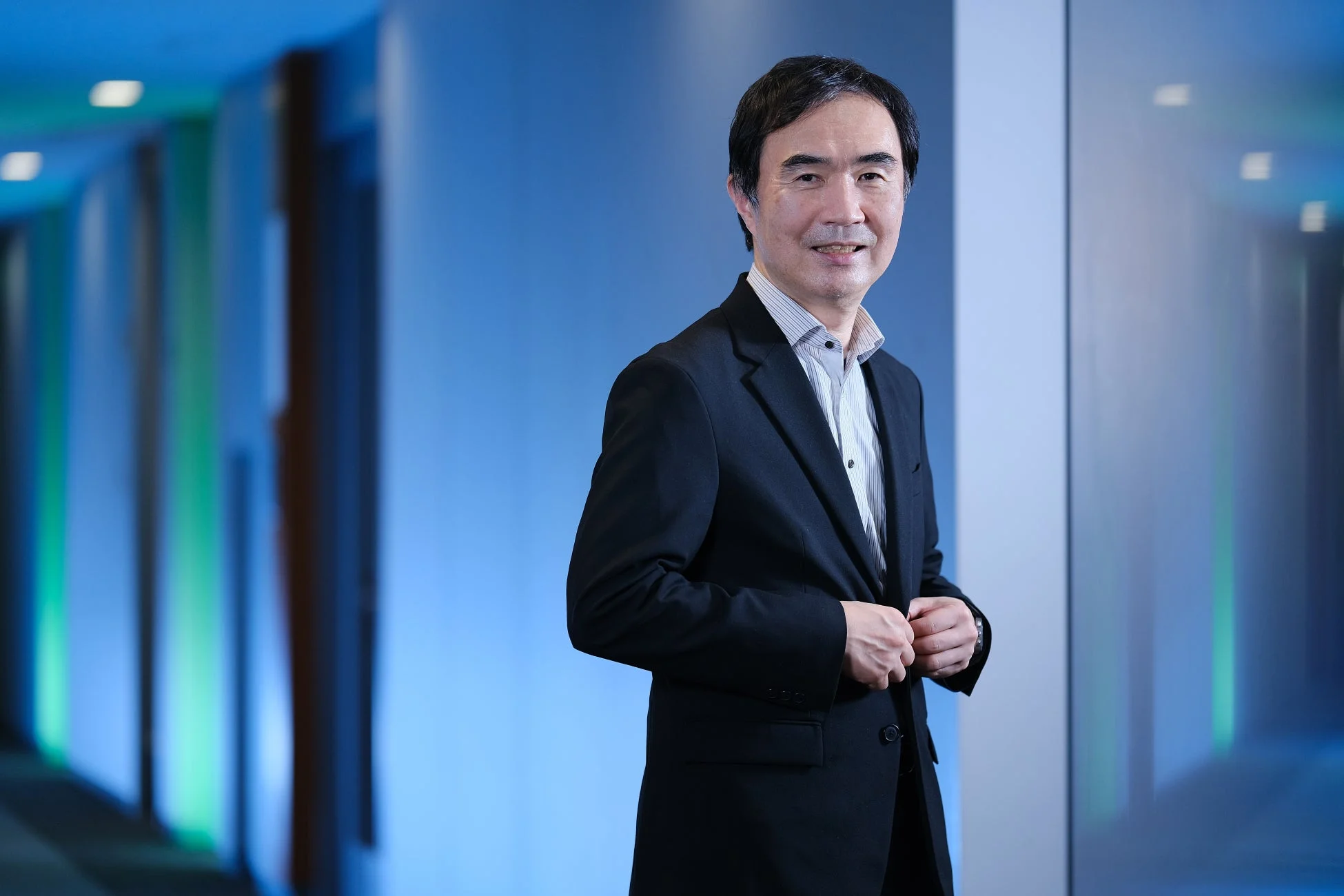 青い照明の通路に立つビジネススーツ姿の男性